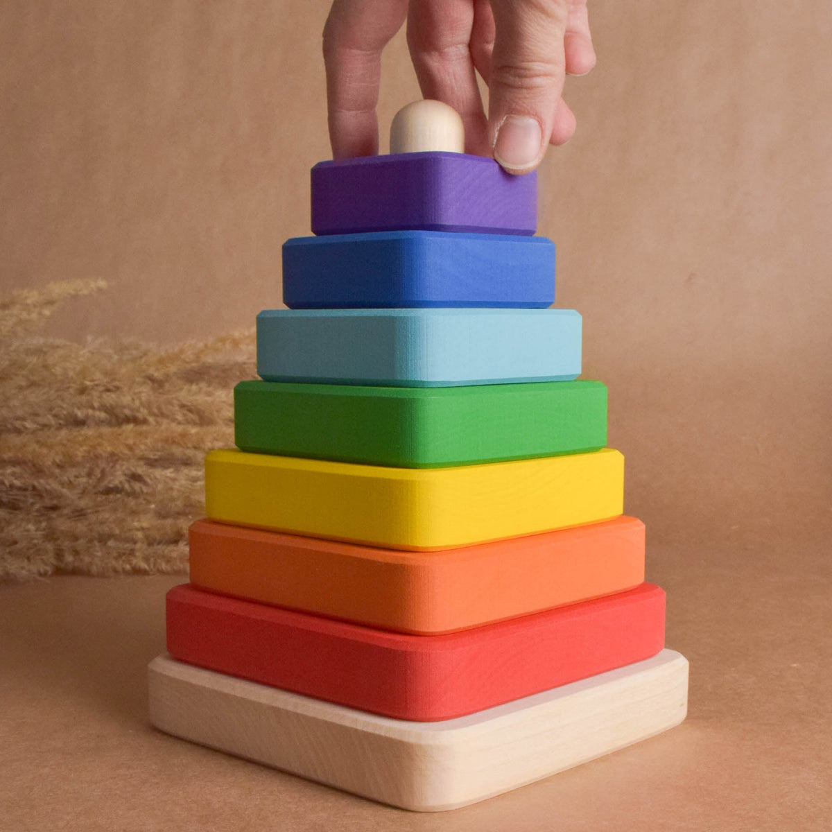 Stacking toy with rainbow-colored square rings made from wood