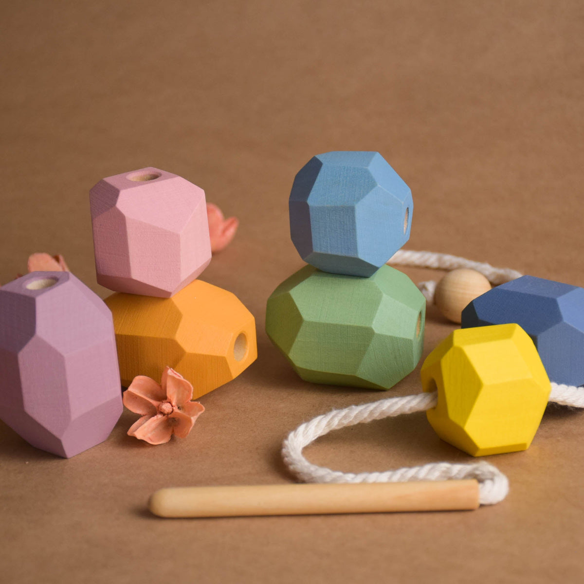 Soft pastel wooden Tumi Ishi stones threaded into a curved line on natural cord for color gradient recognition play