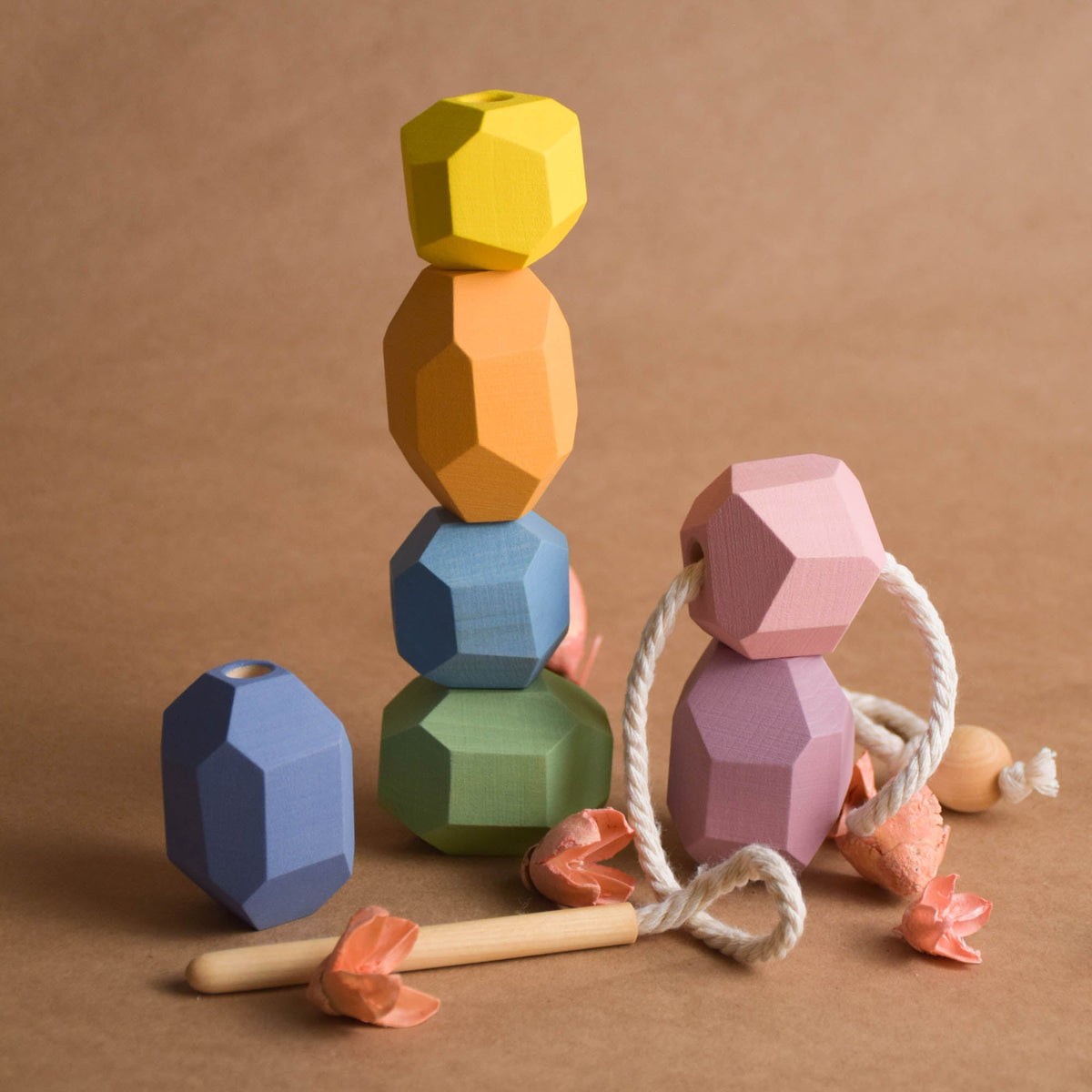 Tower of soft pastel faceted wooden Tumi Ishi stones stacked vertically for balance and coordination play