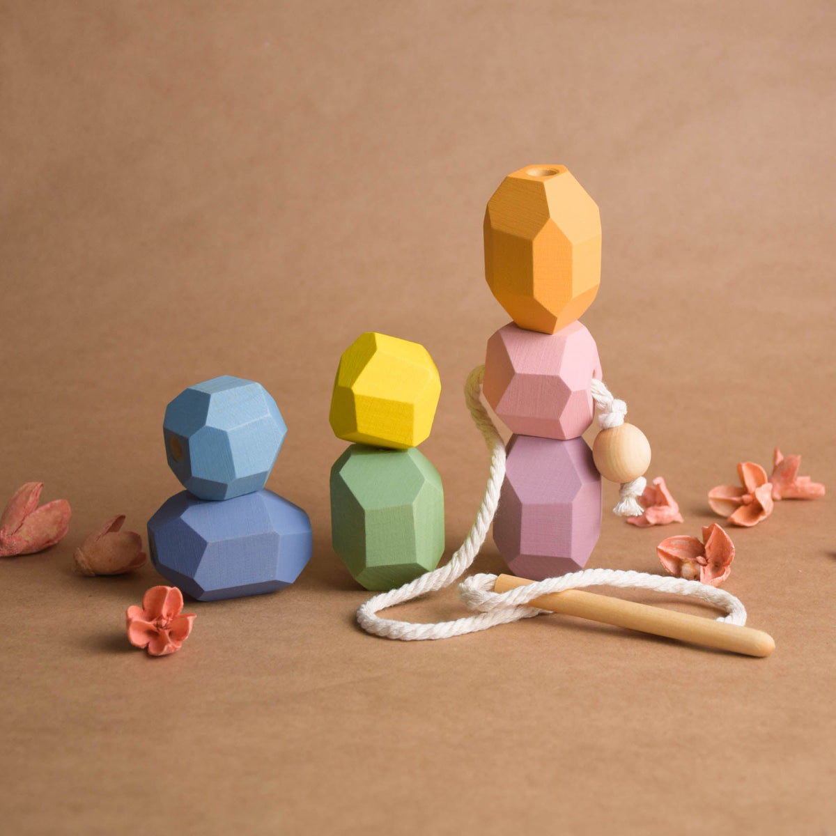 All seven pastel wooden threading stones fully laced onto natural cord lying flat as a colorful rainbow caterpillar