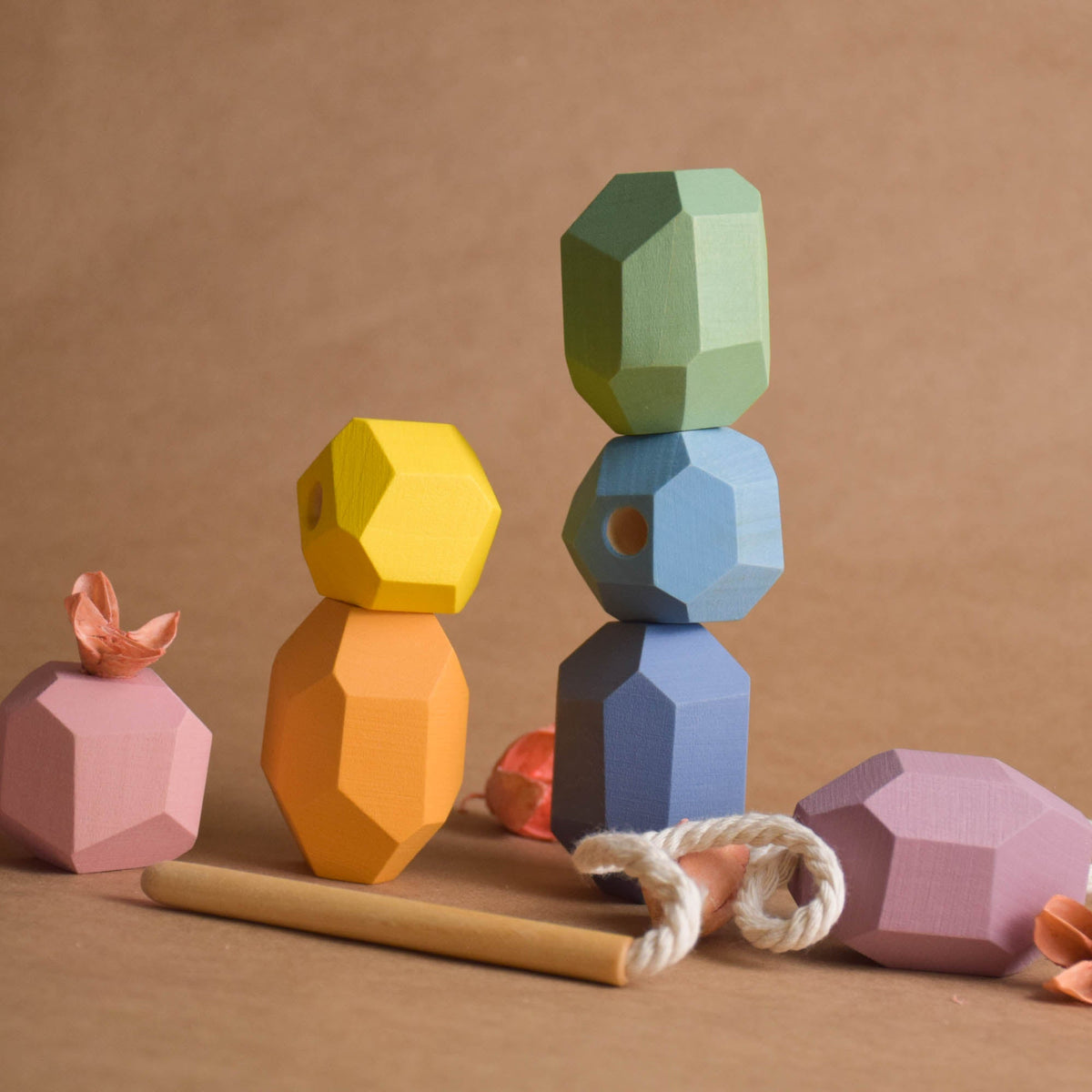 Handmade pastel wooden lacing toy set displayed on nursery wooden shelf as gentle eco-friendly playroom decor