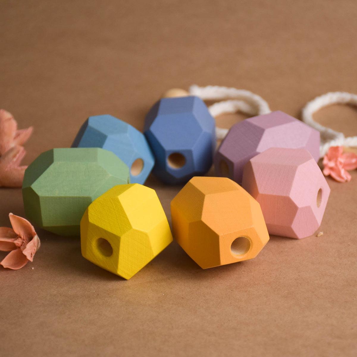 Flat lay of seven pastel wooden threading stones and wooden needle arranged in row for color sorting and counting