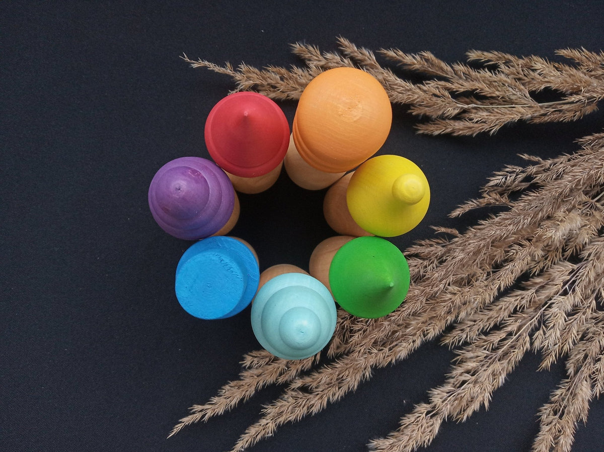 Wooden peg doll figures with rainbow-colored hats